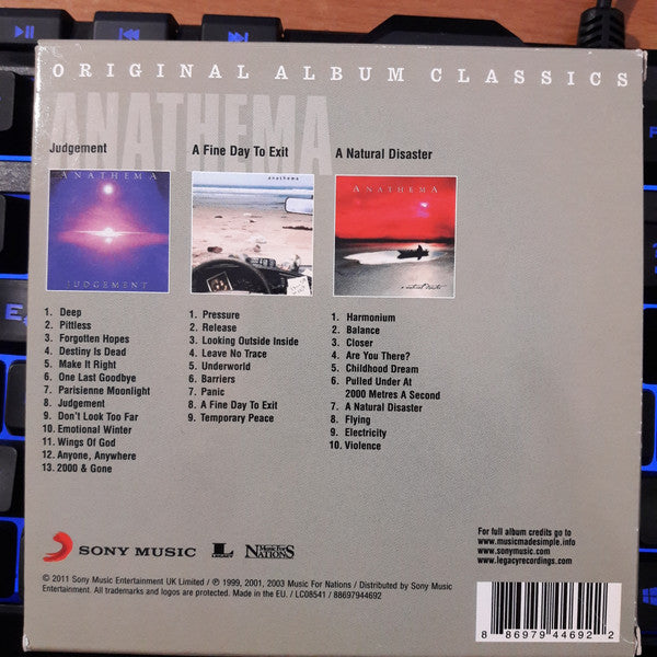 The back cover of a Sony Music CD album for Anastasia, featuring the tracklist, artwork for 'Judgment' and 'A Fine Day To Exit', and 'A Natural Disaster' tracklist on a gray background.