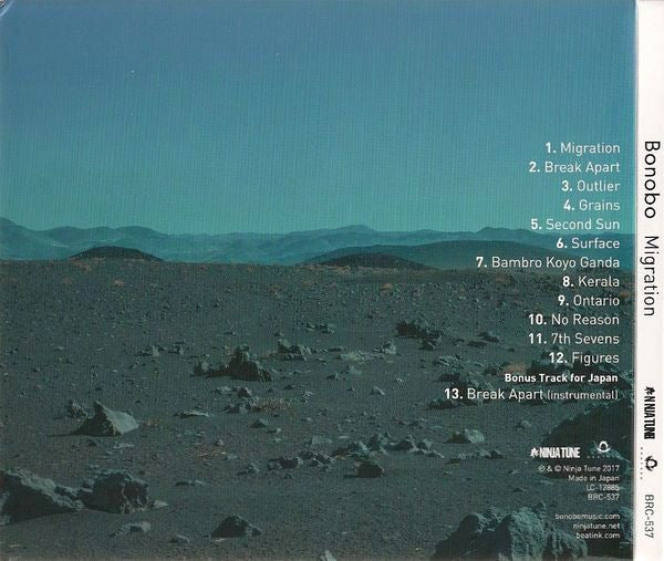 CD cover for Bonobo's 'Migration' album, featuring a scenic landscape photograph of a rocky desert under a teal sky, with tracklist text on the right and the spine visible on the right edge.