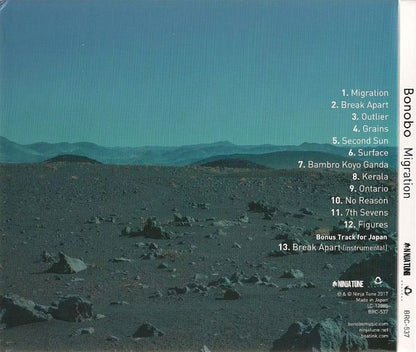 CD cover for Bonobo's 'Migration' album, featuring a scenic landscape photograph of a rocky desert under a teal sky, with tracklist text on the right and the spine visible on the right edge.