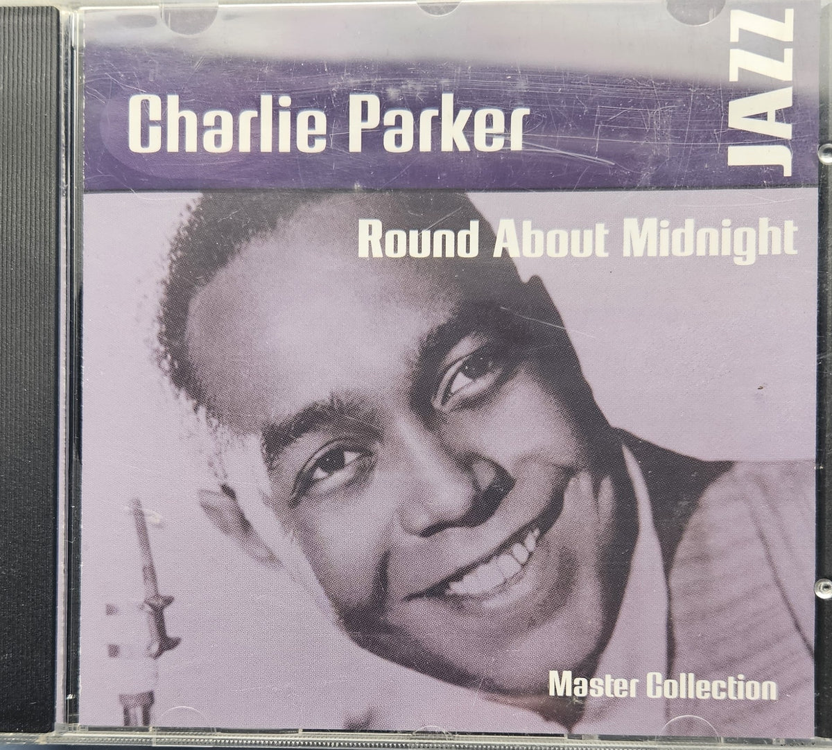 Charlie Parker 'Round About Midnight' Jazz Master Collection CD cover, showing a smiling portrait of Charlie Parker with purple and white text on a light background.