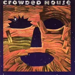Album cover art for 'Crowded House' featuring a stylized, textured face made of orange, red, and yellow wood-like layers with dark starry eye and mouth shapes on a dark blue border.