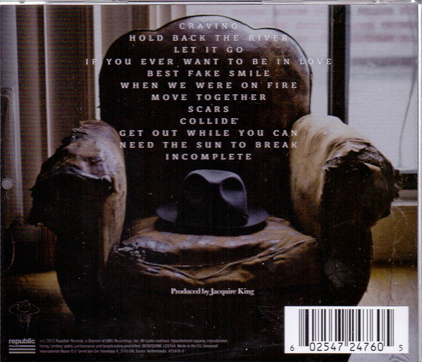 Back cover of a music CD for the band Cradle Of Filth, featuring a dark, moody photograph of a worn armchair with a black hat resting on it, and a list of track titles printed in white text.