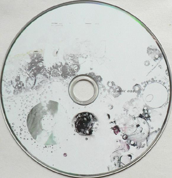 A CD-R disc with abstract black, gray, and white ink-like splatters and smudges across its reflective surface, labeled 'DISC ONE' near the center.