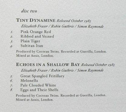 A close-up of a printed tracklist page for Tiny Dynamite's 'Released October 1985' and 'Echoes in a Shallow Bay' with artist names Elizabeth Fraser, Robin Guthrie, and Simon Raymonde.