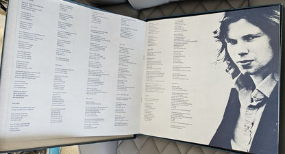 An open book or album booklet laid flat, showing printed text columns on the left page and a black-and-white portrait of a person on the right page.