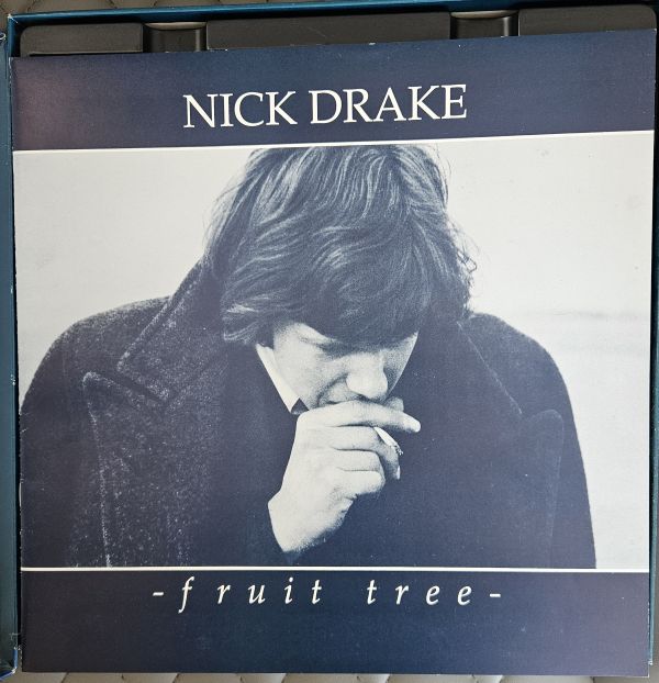 The album cover for Nick Drake's 'fruit tree', featuring a black and white portrait of the artist in a dark coat, with the text 'NICK DRAKE' at the top and '-fruit tree-' at the bottom.