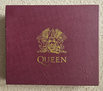 Maroon album cover with gold emblem and 'Queen' text on a textured surface