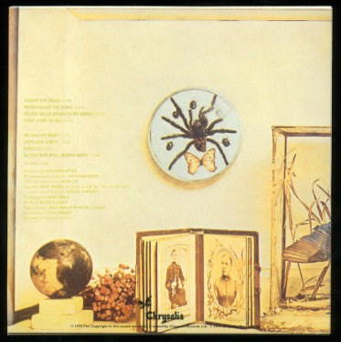 Album cover art for Crystals' 'Invisible Touch' featuring a vintage-style illustration of a spider on a clock, an open book with illustrated pages, a globe, and dried flowers against a warm cream background.