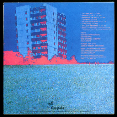 The back cover of the Chrysalis vinyl record album, featuring a stylized graphic of a blue apartment building with bright pink trees against a blue sky, above a textured blue grassy field. The tracklist is printed in white on the right side.