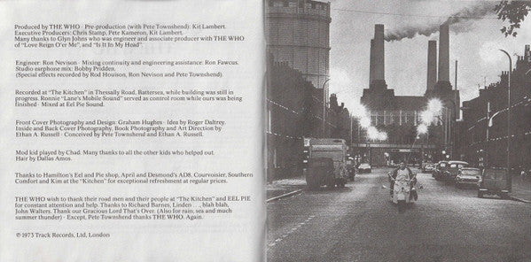 A printed booklet or album insert with a black-and-white street photograph on the right and extensive production credits and track listing text on the left, photographed against a dark background.