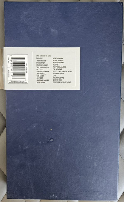A blue hardcover book or album cover with a white barcode label on the left side, photographed from above on a light textured surface.