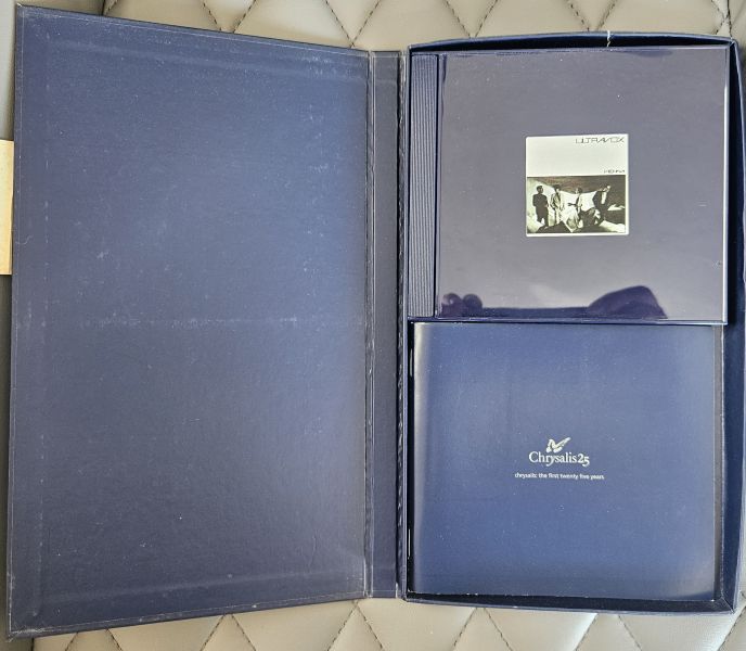 An open dark blue presentation box containing a matching blue booklet/card with the Cignolia logo and a small black-and-white photo insert